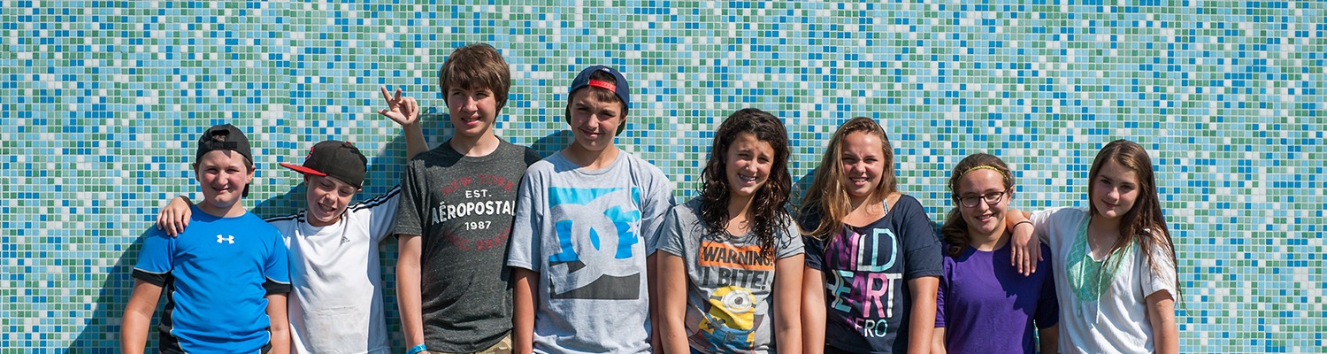 Teens leaning against a blue tiled wall, smiling