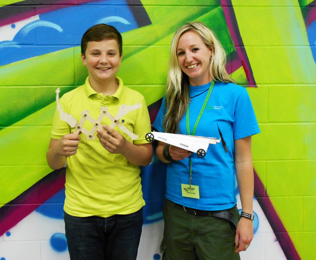 Club staff standing with Club youth, holding STEAM Ahead projects