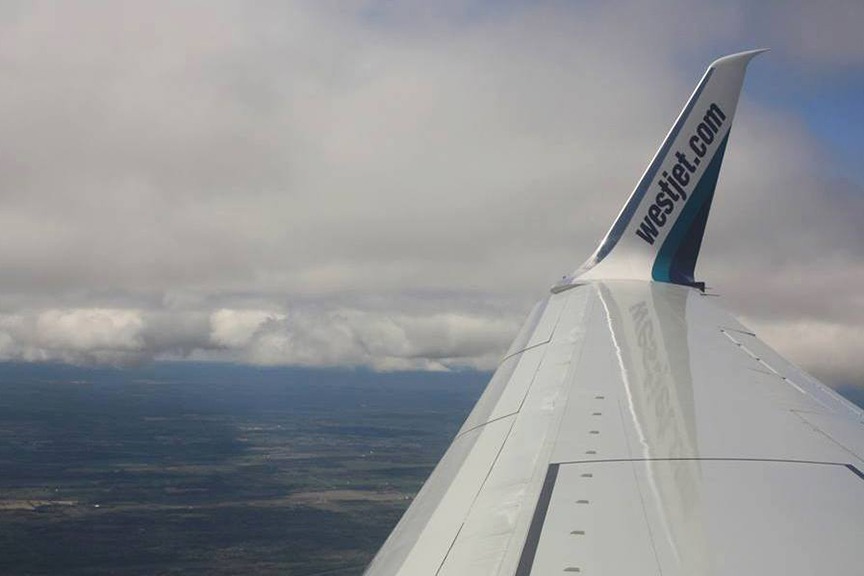 Wing of a WestJet plane, flying